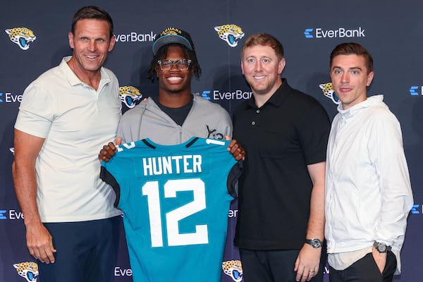 Two-way player Travis Hunter, the Jacksonville Jaguars first round draft pick, second overall, pose with a jersey with general manager James Gladstone, right, head coach Liam Coen, second from right, and executive vice president of football operations Tony Boselli, left, during an NFL football press conference, Friday, April 25, 2025, in Jacksonville, Fla. (AP Photo/Gary McCullough)