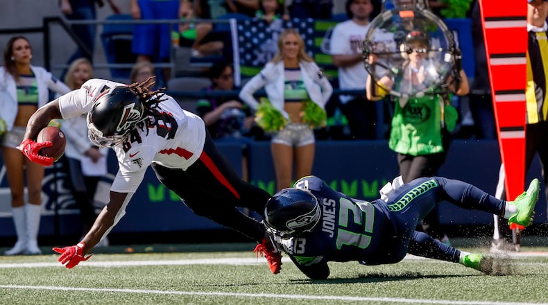 Falcons running back Cordarrelle Patterson dives past Seahawks safety Josh Jones for a 17-yard touchdown during the second quarter Sunday at Lumen Field in Seattle. (Jennifer Buchanan/The Seattle Times/TNS)