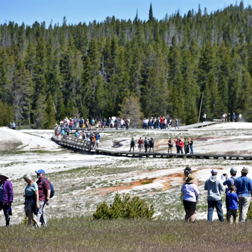 FILE - Tourists walk along a boardwalk in Upper Geyser Basin on June 22, 2022, in Yellowstone National Park, Wyo. (AP Photo/Matthew Brown, File)