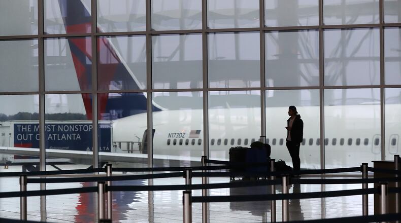 A Delta plane sits at the International Terminal at Hartsfield Jackson International Airport with a solitary traveler waiting for a flight amid new European travel restrictions on Monday, March 16, 2020, in Atlanta. International and domestic air travel have been hammered by the coronavirus. (Curtis Compton/Atlanta Journal-Constitution/TNS)
