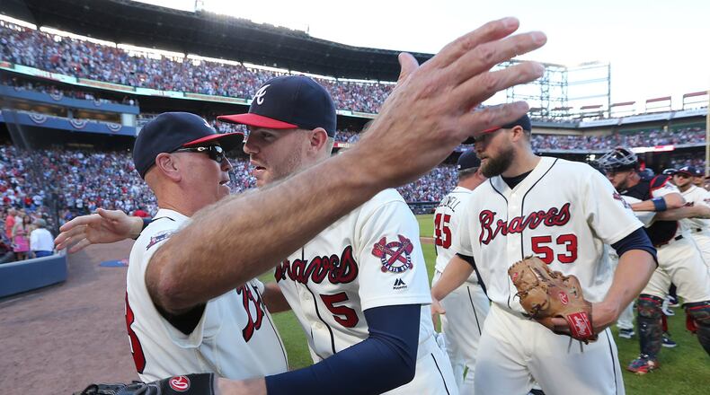 Braves manager Brian Snitker (left) celebrates with Freddie Freeman after he drove in the only run in a season-ending win against Detroit Sunday. Freeman was named NL Player of the Month for September. (Curtis Compton /ccompton@ajc.com)