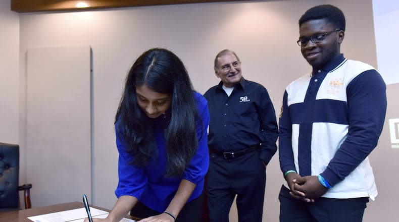 Former student interns Elizabeth Karivelil and Patrick Aghadiuno, both GSMST students, sign an “application note” document as Dr. Simon Yunes (center), senior application scientist at Micromeritics Instrument Corporation. looks on Thursday, April 19, 2018. Micromeritics, a 55-year-old Norcross-based global manufacturer of scientific instruments, has had a longtime commitment to Gwinnett County Public Schools and student development with an internship program. Students this year helped publish a scientific paper on groundbreaking research to help the industry become more efficient in a manufacturing process. HYOSUB SHIN / HSHIN@AJC.COM