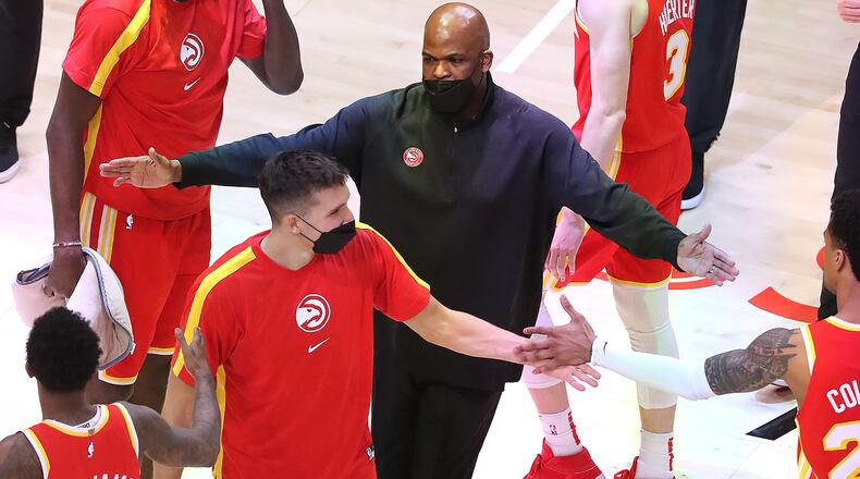 Hawks interim coach Nate McMillan hands out fives to his players during a victory on April 20, 2021. (Curtis Compton / Curtis.Compton@ajc.com)
