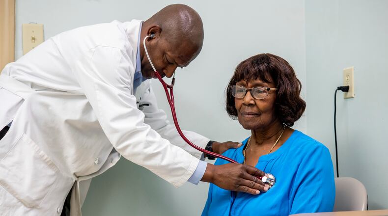 Morris Brown, a primary care physician, listens to Sarah McCutcheon’s heartbeat in the exam room at his medical office in Kingstree, South Carolina, which sits in a region that suffers from health care provider shortages and high rates of chronic diseases. (Gavin McIntyre/KFF Health News/TNS)