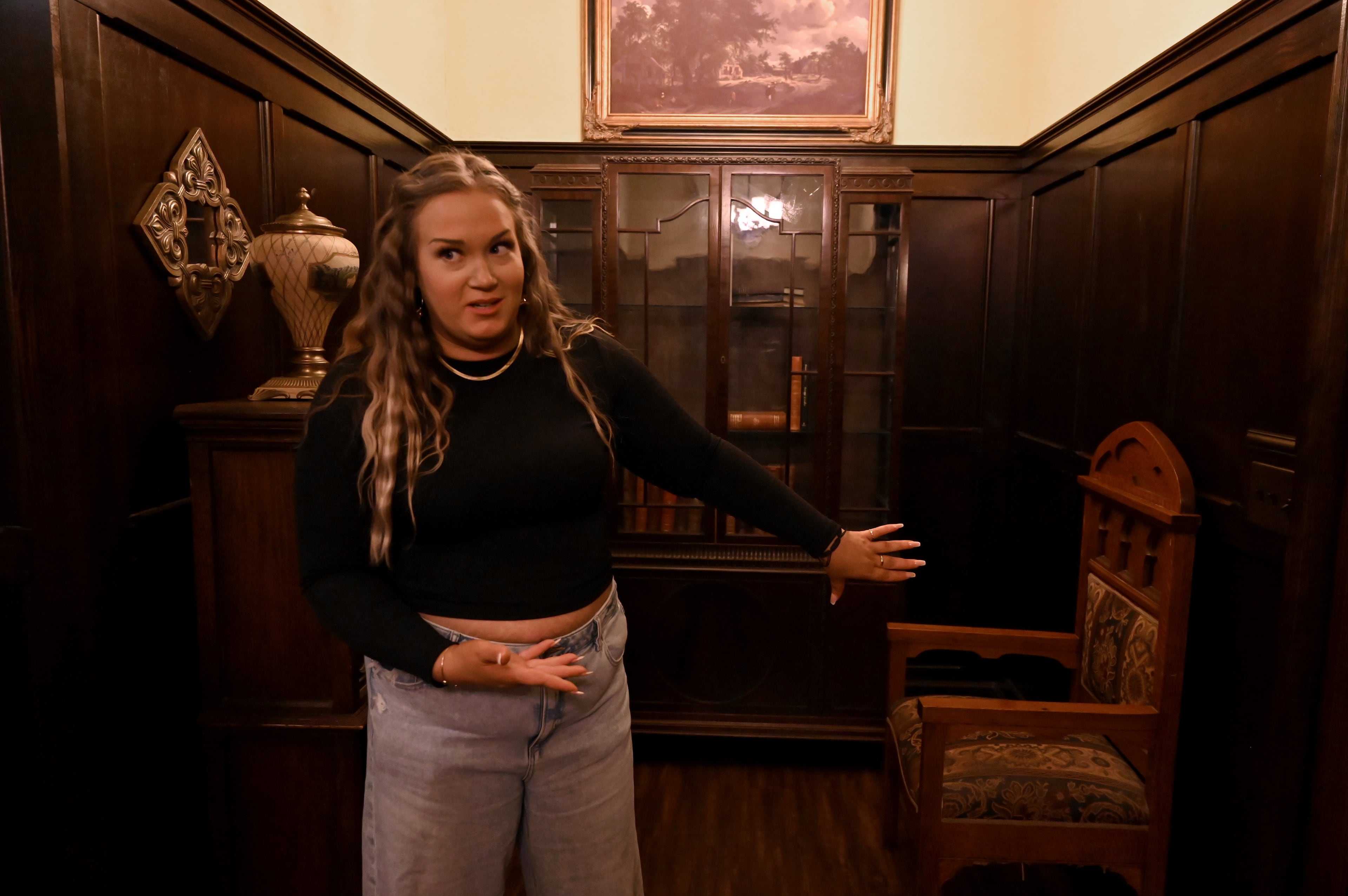 Jamie Cook, a tour coordinator at the Mystic Mercantile's meticulously recreated set of the Salvatore brothers' living room, shows off the fan favorite "torture chair" set piece from "The Vampire Diaries." (Hyosub Shin/AJC)