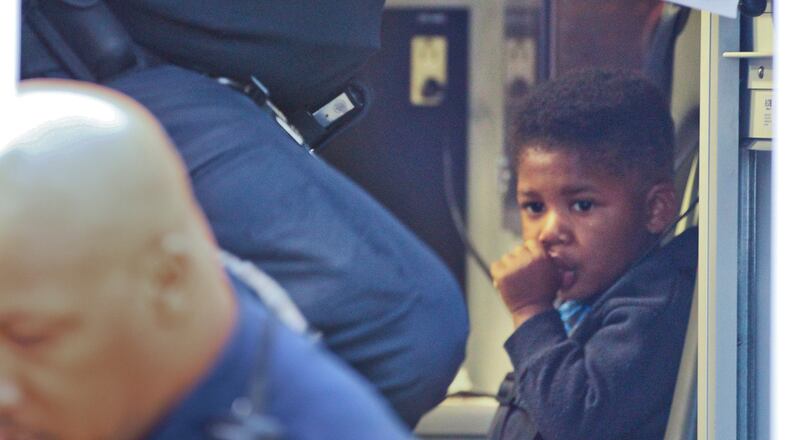 Atlanta police officers exit a Grady ambulance after talking with a mother and her 2-year-old child who was ticketed by police after stepping in front of a vehicle while trying to catch a bus on Peachtree and Alabama streets Friday morning, police said. The unidentified woman was cited for pedestrian in a roadway.