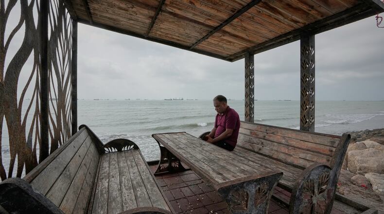 A man rests at a waterfront shelter as commercial vessels lie anchored in the Strait of Hormuz off Bandar Abbas, Iran, Friday, Sept. 4, 2026. (AP Photo/Vahid Salemi)