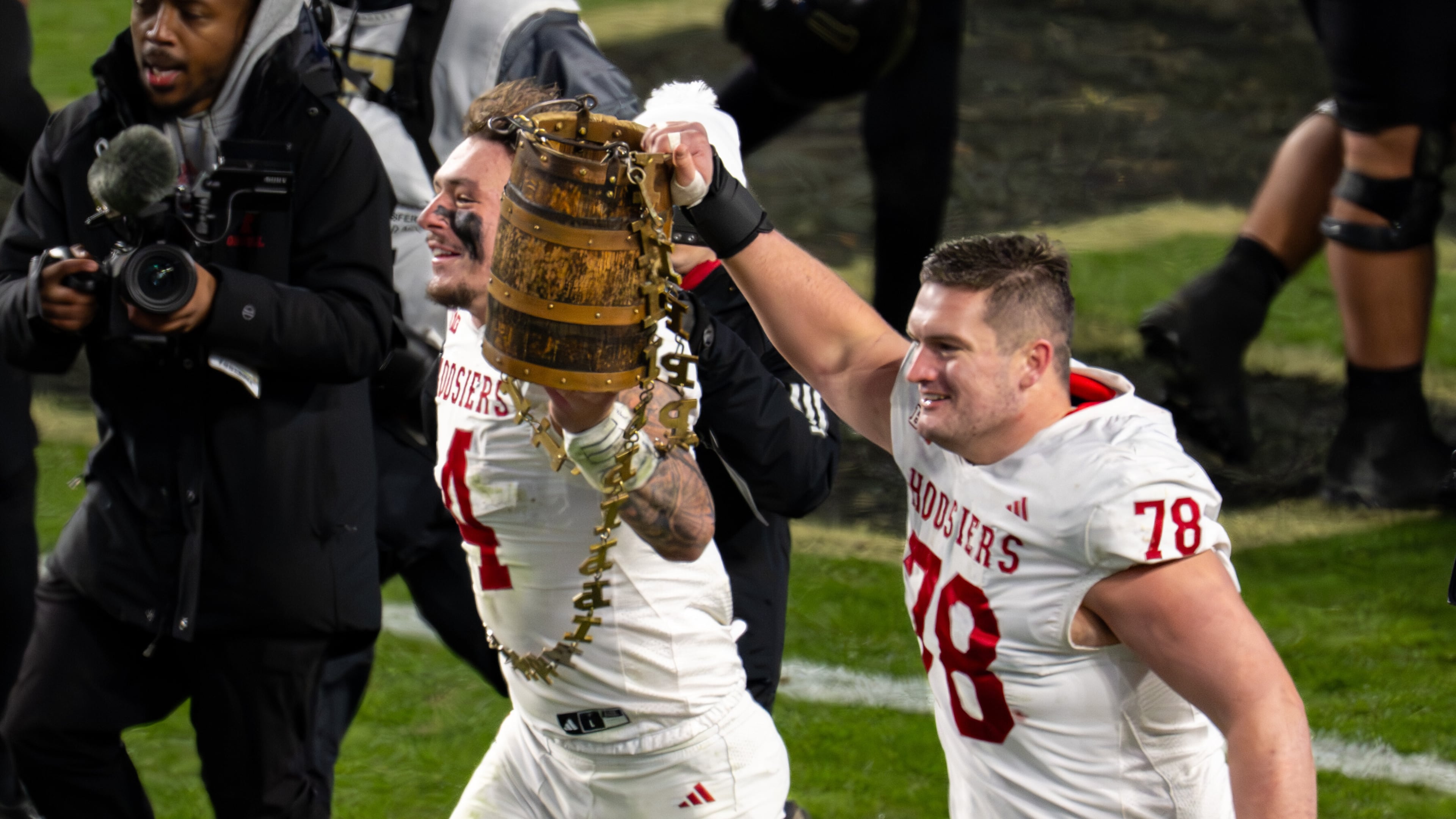 Indiana linebacker Aiden Fisher (4) and offensive lineman Pat Coogan (78) celebrate with the Old Oaken Bucket trophy after an NCAA college football game against Purdue, Friday, Nov. 28, 2025, in West Lafayette, Ind. (AP Photo/Doug McSchooler)