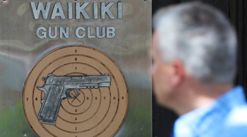 FILE - People walk past the Waikiki Gun Club, Thursday, June, 23, 2022 in Honolulu. (AP Photo/Marco Garcia)