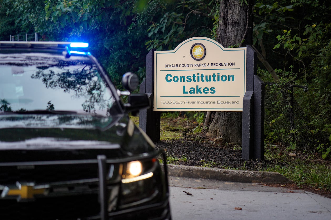 A police cruiser blocks the entrance to Constitution Lakes Park on Friday after a deadly double shooting. (Ben Hendren for the AJC)