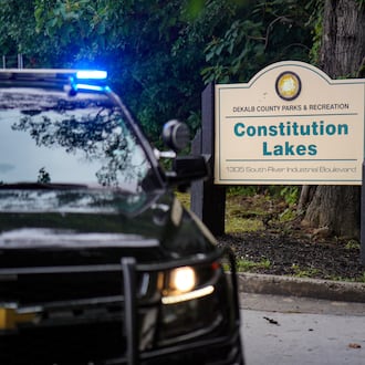 A police cruiser blocks the entrance to Constitution Lakes Park on Friday after a deadly double shooting. (Ben Hendren for the AJC)
