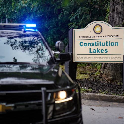 A police cruiser blocks the entrance to Constitution Lakes Park on Friday after a deadly double shooting. (Ben Hendren for the AJC)