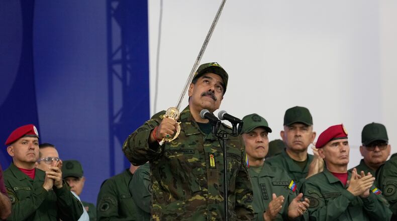 Venezuelan President Nicolas Maduro brandishes a sword said to have belonged to independence hero Simon Bolivar during a civic-military event at the military academy in Caracas, Venezuela, Tuesday, Nov. 25, 2025. (AP Photo/Ariana Cubillos)