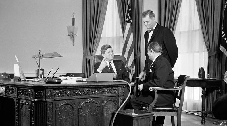 FILE - President John F. Kennedy gestures from behind a richly carved desk, made from the timbers of a British sailing ship, as he talks, Feb. 6, 1961 in his White House office in Washington with Mongi Slim, right, Tunisian Ambassador to the U.S., and G. Mennen Williams, Assistant Secretary of State for African Affairs. (AP Photo/HB, File)