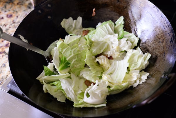 Torn cabbage leaves about to be stir-fried in a wok.
