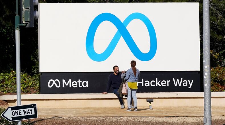 FILE - People talk near a Meta sign outside of the company's headquarters in Menlo Park, Calif., March 7, 2023. (AP Photo/Jeff Chiu, File)