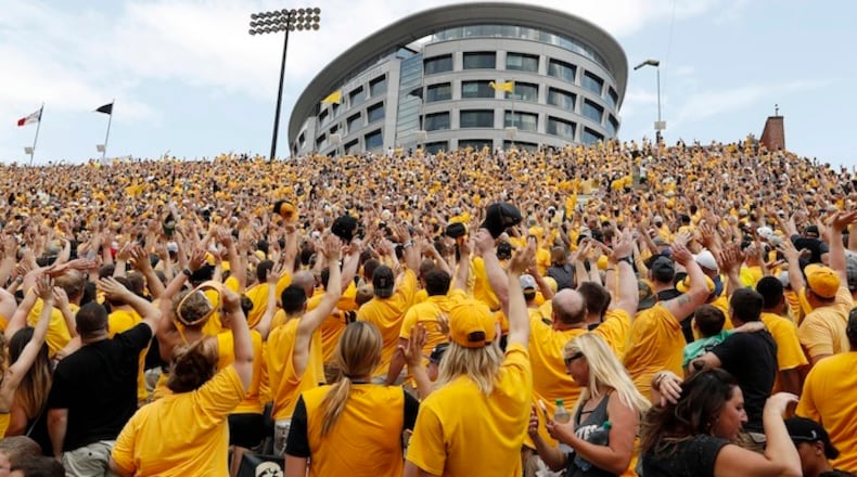 In this Sept. 16, 2017, file photo, Iowa fans wave towards fans watching from University of Iowa's children's hospital at the end of the first quarter of an NCAA college football game against North Texas in Iowa City, Iowa. In the new tradition, known as The Wave, at the end of the first quarter fans in the 70,585-seat Kinnick Stadium turn to wave to the pediatric patients watching from the hospital, a 12-story building that overlooks the stadium from across the street. (AP Photo/Charlie Neibergall, File)