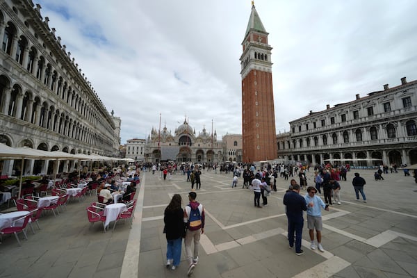 People walk in San Marco square in Venice, Italy, Friday, April 18, 2025, Venice on Friday launches for a second year a pilot program to charge day-trippers an entrance fee. (AP Photo/Antonio Calanni)