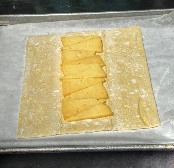 Two Urban Licks executive chef Shain Wancio, making a savory puff pastry galette, has placed the foundation of Thomasville Tomme cheese on top of the puff pastry. (Styling by chef Shain Wancio / Chris Hunt for the AJC)