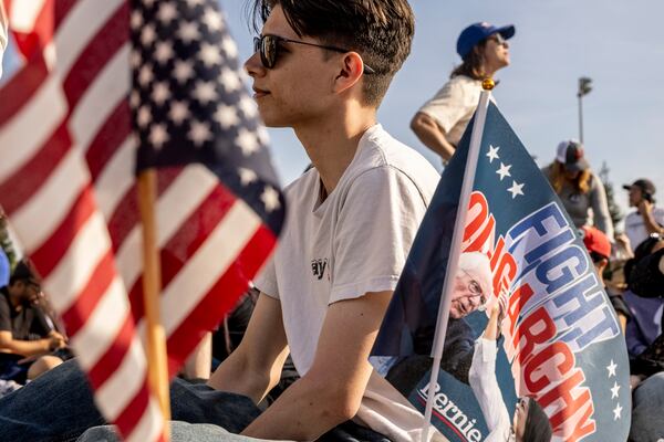 Ethan Jackline, sits next to a flag planted by a friend as they attend a 'Fighting Oligarchy' rally with Sen. Bernie Sanders (I-VT) and Rep. Alexandria Ocasio-Cortez (D-NY) in Folsom, Calif., Tuesday, April 15, 2025. (Stephen Lam/San Francisco Chronicle via AP)