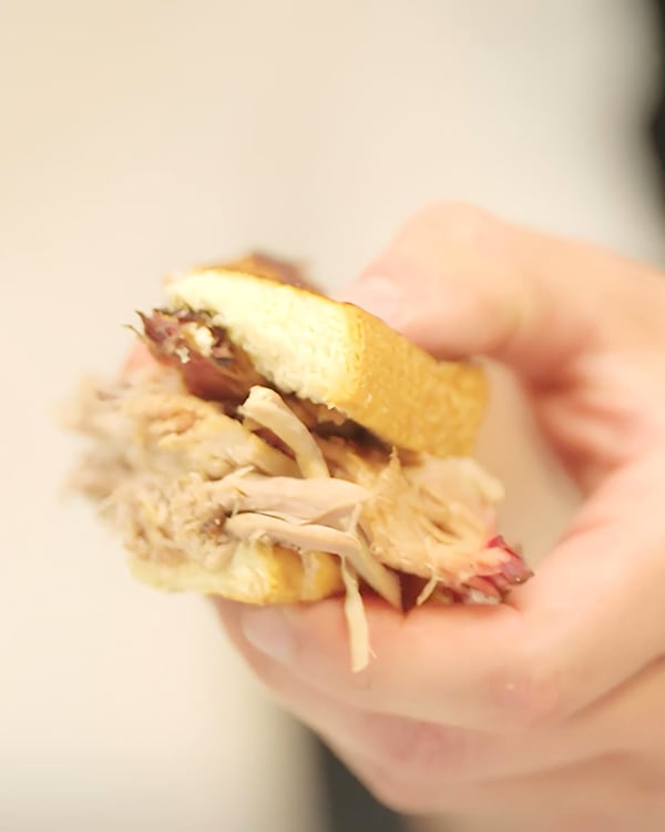 An AJC taste tester holds a quarter of a pulled pork sandwich.