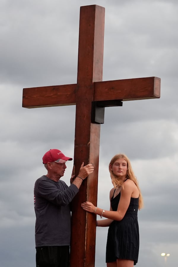 Dan Beazley, of Michigan, left, and Abigail Smithson hold a large cross during a vigil for flooding victims at Tivy Antler Stadium on Wednesday, July 9, 2025, in Kerrville, Texas. (AP Photo/Gerald Herbert)
