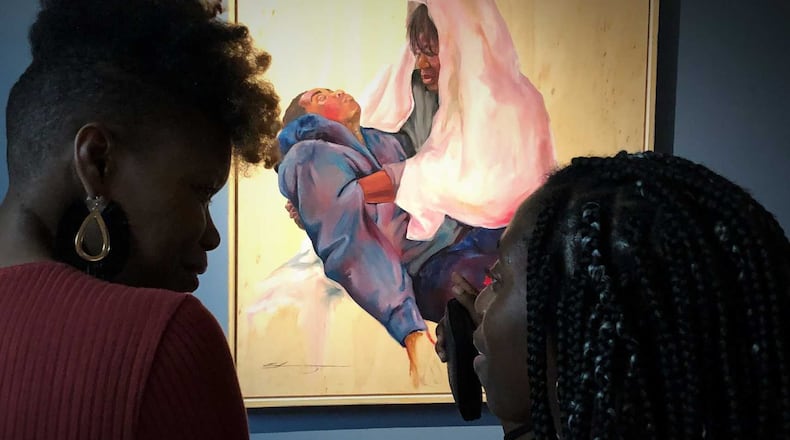 Shanequa Gay (left) discusses her painting "La Pieta," with Isuan Oyakhire, an Oglethorpe senior biopsychology major, after its unveiling at the university’s art museum.