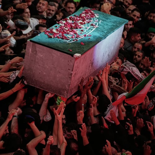 The flower petal-covered coffin of the late Iranian Supreme Leader Ayatollah Ali Khamenei is carried above mourners reaching out to touch it outside the Imam Hussein Shrine in Karbala, Iraq, early Thursday, July 9, 2026. (AP Photo/Khalil Hamra)