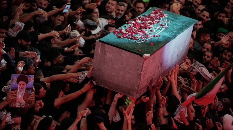 The flower petal-covered coffin of the late Iranian Supreme Leader Ayatollah Ali Khamenei is carried above mourners reaching out to touch it outside the Imam Hussein Shrine in Karbala, Iraq, early Thursday, July 9, 2026. (AP Photo/Khalil Hamra)