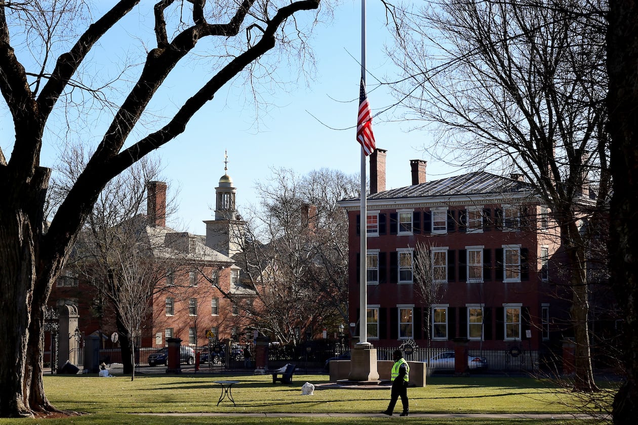 A security guard walks past a flag at half-staff on the main green of Brown University in Providence, RI, Thursday, Dec. 18, 2025, (AP Photo/ Mark Stockwell)