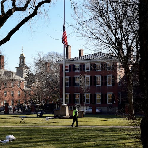 A security guard walks past a flag at half-staff on the main green of Brown University in Providence, RI, Thursday, Dec. 18, 2025, (AP Photo/ Mark Stockwell)
