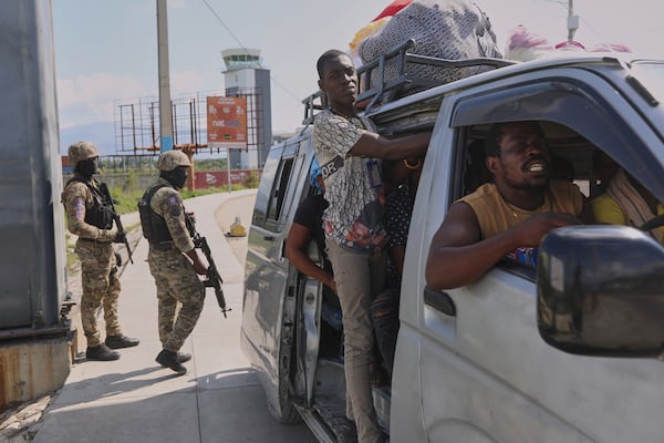 Commuters pass by police patrolling an intersection in Port-au-Prince, Haiti, Friday, May 9, 2025. (AP Photo/Odelyn Joseph)