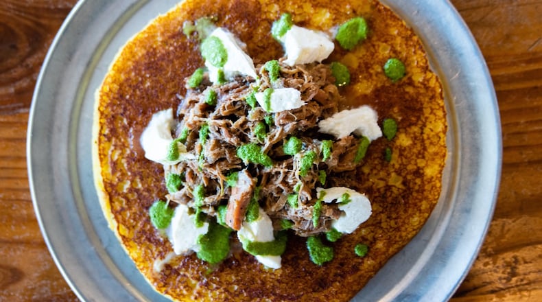 The cachapa pernil at Arepa Mia is topped with roasted pork cooked in mojo sauce, caramelized onion, cilantro and guayanes cheese.