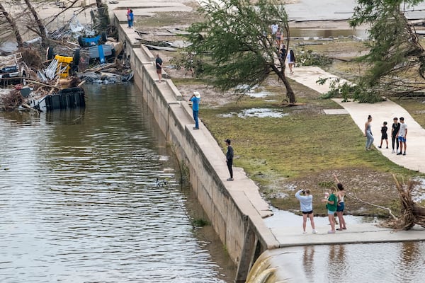 Onlookers walk along the banks of the Guadalupe River in Louise Hays Park, Saturday, July 5, 2025, in Kerrville, Texas. (AP Photo/Rodolfo Gonzalez)