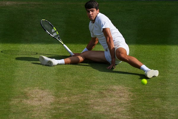 Carlos Alcaraz of Spain slips as he returns a shot by Italy's Jannik Sinner in the men's singles final at the Wimbledon Tennis Championships in London, Sunday, July 13, 2025. (AP Photo/Joanna Chan)