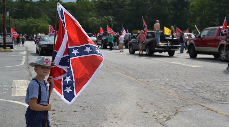 A young Confederate flag supporter stands in the Yellow Daisy parking lot at Stone Mountain Park as more caravans stream in. DANIEL FUNKE / DANIEL.FUNKE@COXINC.COM