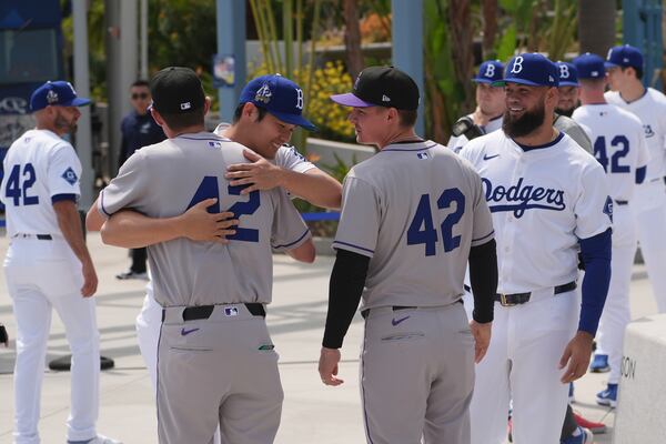 Los Angeles Dodgers' Shohei Ohtani, left, hugs teammates at Dodger Stadium during an event to commemorate Jackie Robinson Day before a baseball game against the Colorado Rockies Tuesday, April 15, 2025, in Los Angeles. (AP Photo/Damian Dovarganes)