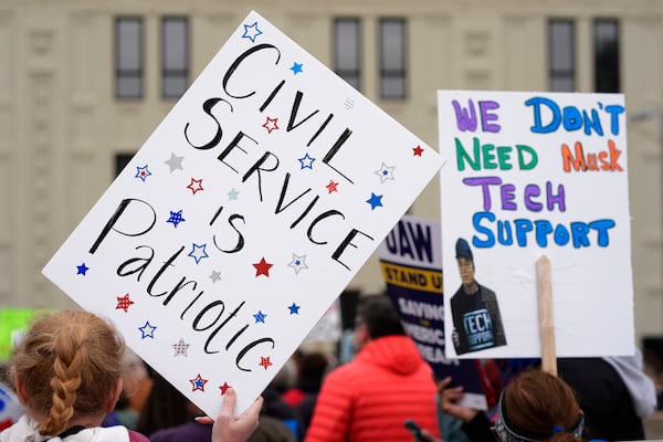 People hold signs at a rally supporting federal workers outside the IRS regional office Saturday, March 15, 2025, in Kansas City, Mo. (AP Photo/Charlie Riedel)