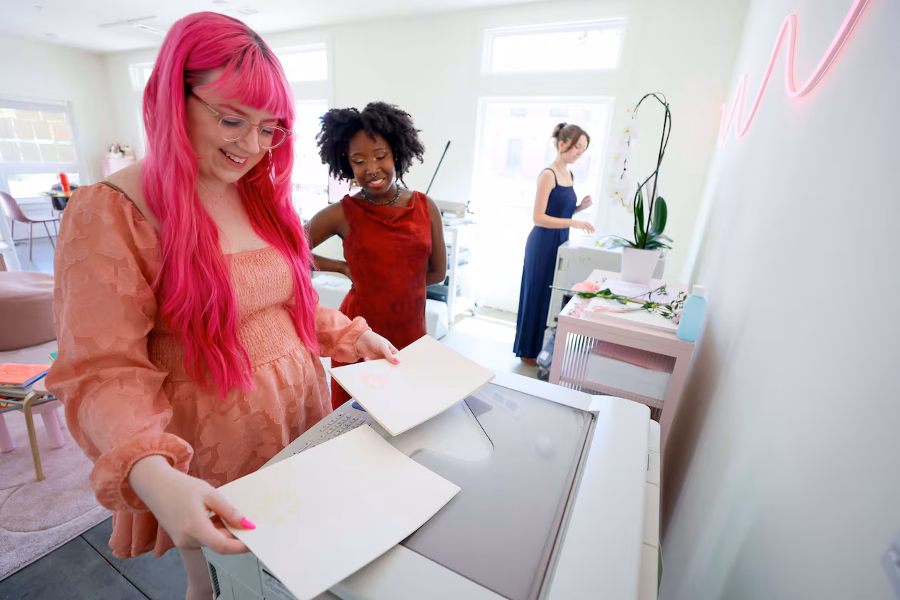 Posy Press studio founder Samantha Richardson (left) shares a smile with workshop instructor Arantza Peña Popo as they eye a Risograph machine print at the Goat Farm arts complex. (Miguel Martinez/AJC)