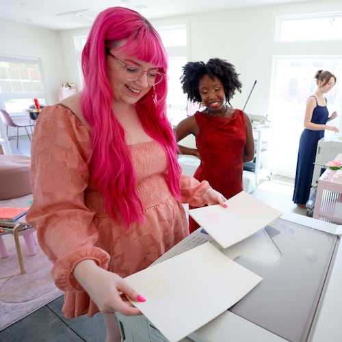 Posy Press studio founder Samantha Richardson (left) shares a smile with workshop instructor Arantza Peña Popo as they eye a Risograph machine print at the Goat Farm arts complex. (Miguel Martinez/AJC)