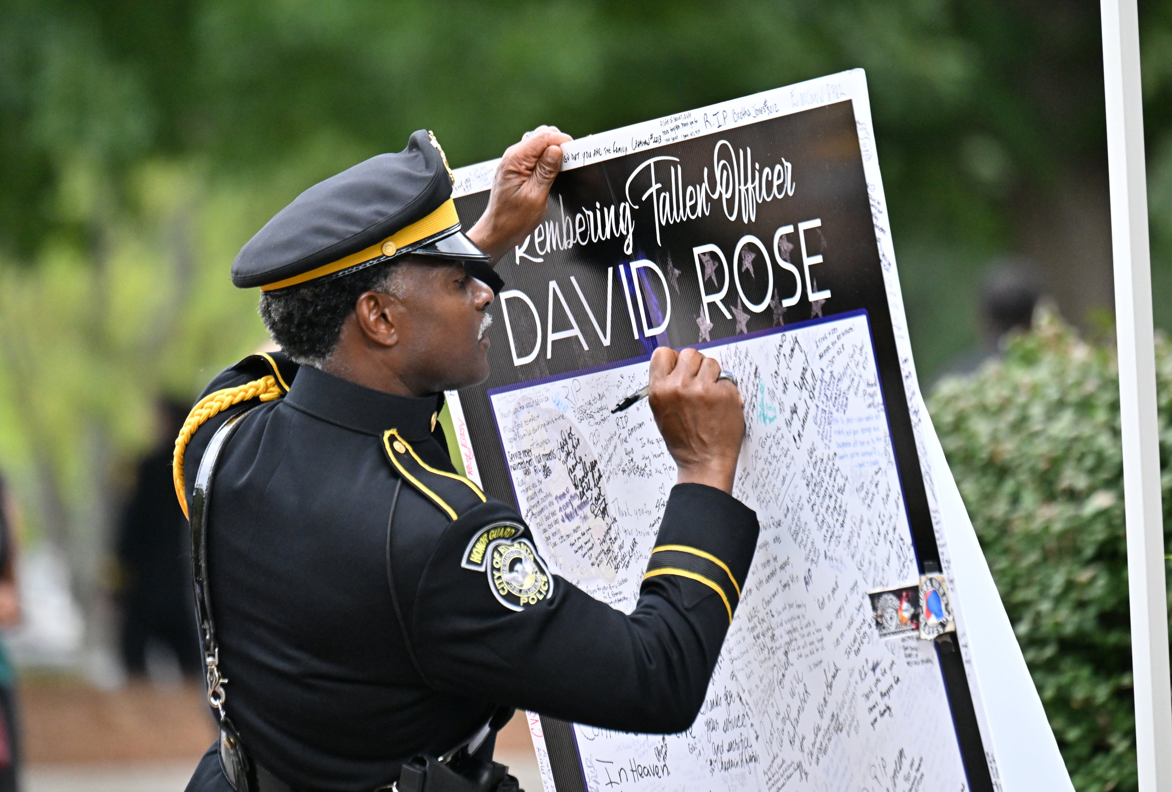 A mourner writes a message before the start of the memorial service for fallen DeKalb County police Officer David Rose at First Baptist Church Atlanta, Friday, August 22, 2025. Rose was killed while responding to the Aug. 8 shooting at the CDC. (Hyosub Shin/AJC)