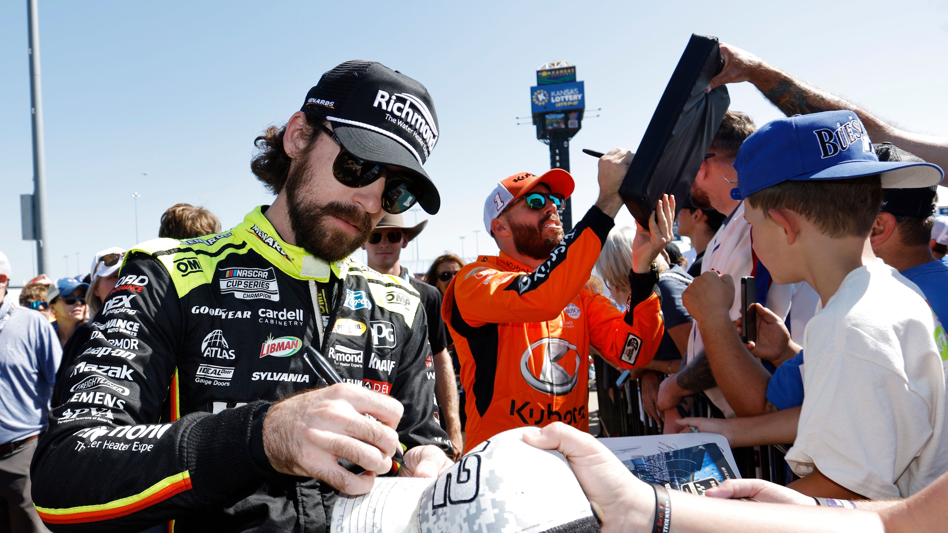 CORRECTS TO ROSS CHASTAIN NOT BUBBA WALLACE - Ryan Blaney, left, and Ross Chastain, center, give autographs before a NASCAR Cup Series auto race at Kansas Speedway in Kansas City, Kan., Sunday, Sept. 28, 2025. (AP Photo/Colin E. Braley)