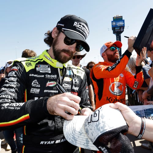 CORRECTS TO ROSS CHASTAIN NOT BUBBA WALLACE - Ryan Blaney, left, and Ross Chastain, center, give autographs before a NASCAR Cup Series auto race at Kansas Speedway in Kansas City, Kan., Sunday, Sept. 28, 2025. (AP Photo/Colin E. Braley)