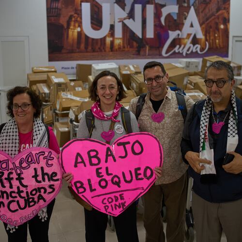 CODEPINK activists hold signs in front of boxes of aid they brought as part of the "Nuestra America," or Our America Convoy, after landing at the airport in Havana, Cuba, Friday, March 20, 2026. (AP Photo/Ramon Espinosa)