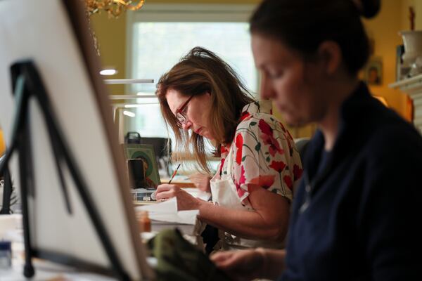 Katherine Fristoe (center) works next to Rachel Grantham as they paint their icons at Nancy Ewing’s home. (Jason Getz/AJC)