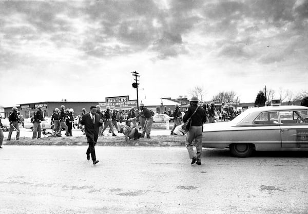 In this March 7, 1965, file photo, march leader Hosea Williams, left, leaves the scene as state troopers break up the civil rights voter registration march in Selma, Ala., and put John Lewis, center, of the Student Nonviolent Coordinating Committee on the ground.  (AP Photo/File)