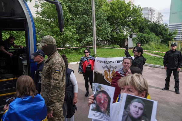 Olha Kurtmalaieva holds a placard for Ukrainian marine soldiers coming out from a bus after a POWs exchange between Russia and Ukraine, in Chernyhiv region, Ukraine, Saturday, June 14, 2025. (AP Photo/Evgeniy Maloletka)