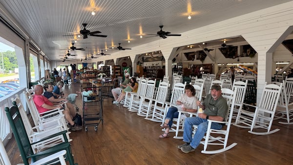 Customers at Dickey Farms relax on rocking chairs in the shade of the peach packinghouse in Musella on Sunday, June 22, 2025. (Joe Kovac Jr./AJC)