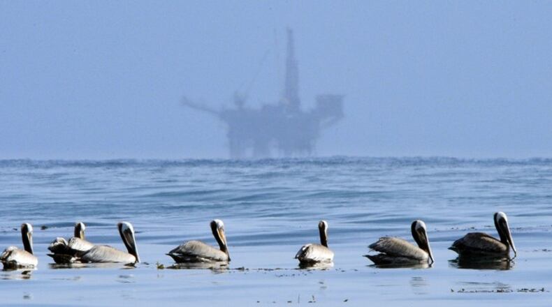 In this May 13, 2010 file photo, pelicans float on the water with an offshore oil platform in the background off the coast of Santa Barbara, Calif. (AP Photo/Mark J. Terrill, File)