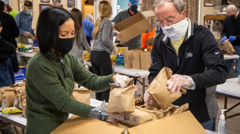 Mai Nguyen (left) and Jim Hinkle load lunch bags into boxes after American Legion Post 140 Buckhead members and their family members assembled 2,000 them for USO Operation: Holiday Block Leave. PHIL SKINNER FOR THE ATLANTA JOURNAL-CONSTITUTION.